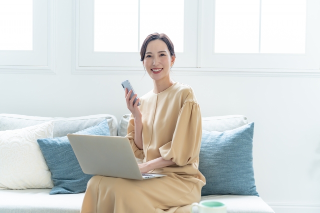 リビングのソファーで携帯をする女性